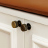 Knob with grooved surface in antique finish on a white bench seat with leather s